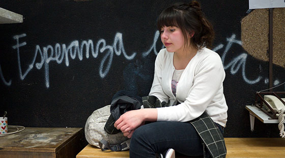 Woman sitting on desk in front of chalkboard